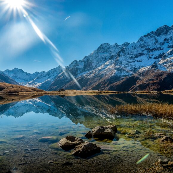 Beautiful shot of a crystal clear lake next to a snowy mountain base during a sunny day